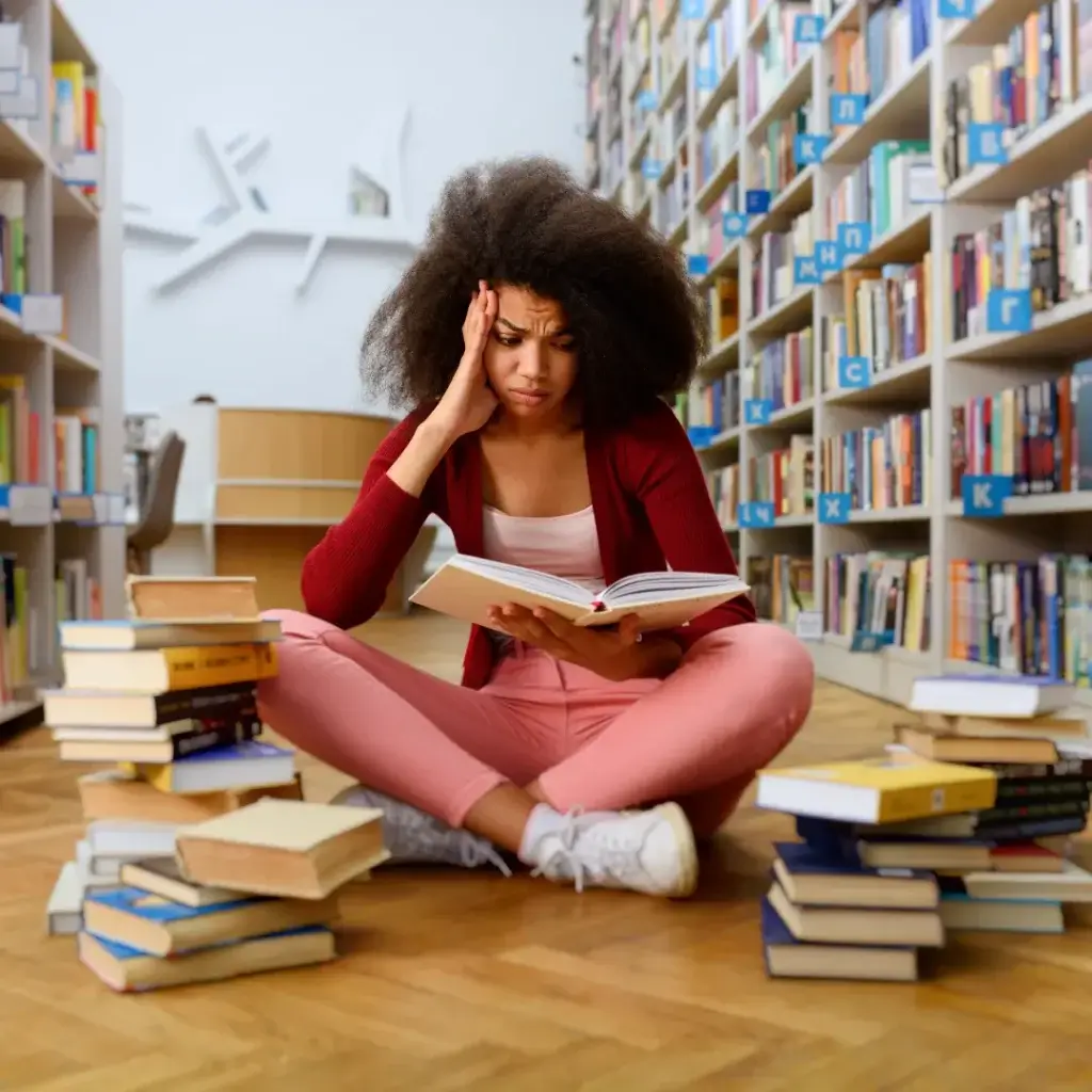 méthode-travail-lycée-1 fille qui regarde un livre de physique et éprouve des difficultés en physique chimie. elle se tient le visage et éprouve de la peine à comprendre.