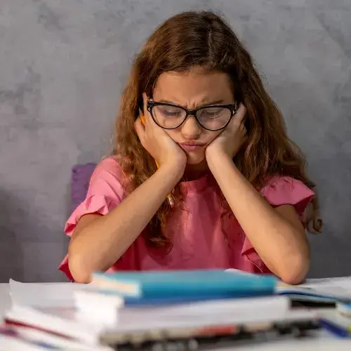 collégienne qui regarde un livre de mathématiques et éprouve des difficultés. elle se tient le visage, la tête baissée