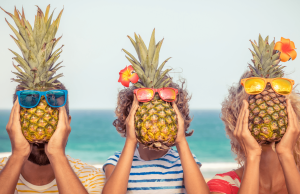 3 enfants cachant leurs visage avec un ananas